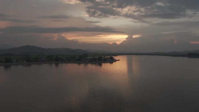 Sunset over Lak Lake in Lien Son Lak Commune, Dak Lak Province, Vietnam, featuring traditional wooden boats on the lake and peaceful rice fields surrounded by the Central Highlands landscape.