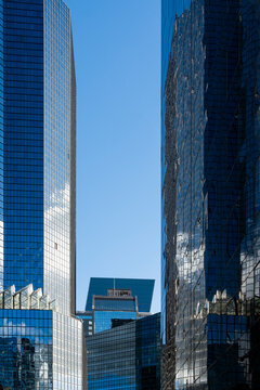 Skyscraper towers in La Defense, Paris, France rise through blue glass reflection, giving the financial office facade strong vertical depth