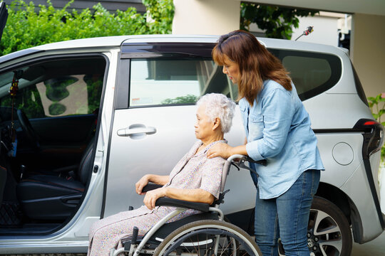 Caregiver help Asian elderly woman disability patient use wheelchair to get in car.