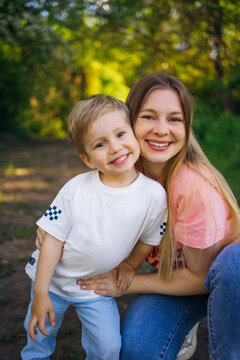 Smiling mother and young son hugging outdoors in a sunlit park casual family portrait