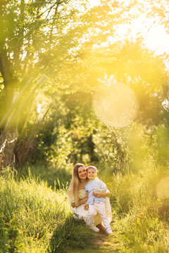 Mother and son smiling together in a sunlit meadow during golden hour family portrait