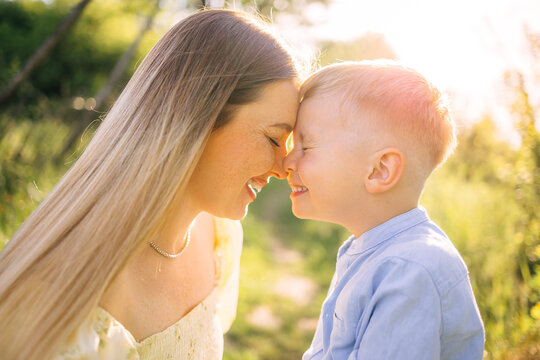 Mother and son sharing a joyful nose-to-nose moment outdoors in warm golden hour light