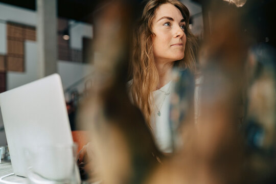 Thoughtful businesswoman looking away while working at shared coworking space
