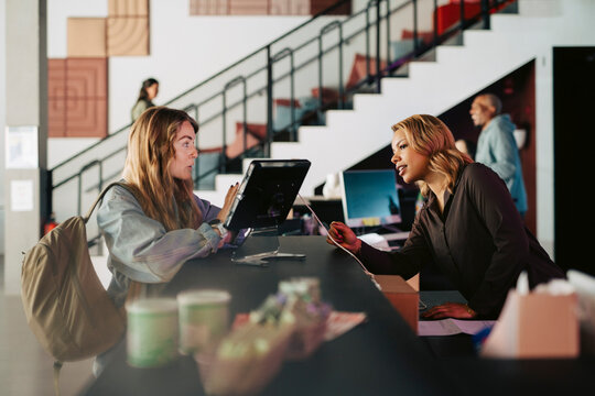 Female receptionist assisting businesswoman doing registration at modern coworking spa
