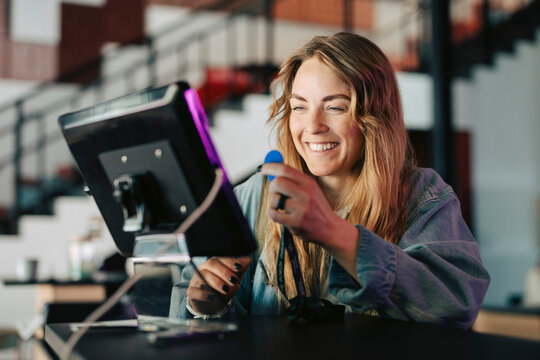 Happy businesswoman using key fob to tap into digital tablet reader at coworking space