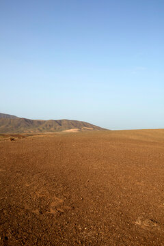 Minimalist volcanic gravel plain with Fem&eacute;s mountain and blue sky, Lanzarote