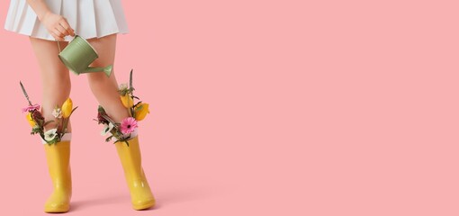 woman in yellow rain boots filled with spring flowers holding watering can on pink background, creative fashion gardening concept with copy space © Pixel-Shot