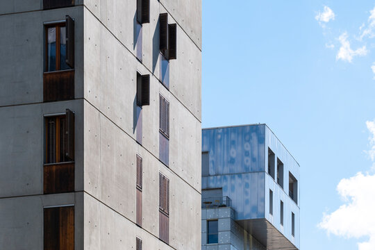 Concrete apartment facade rises beside blue sky in La Confluence, Lyon, France, where windows and shadow give the residential block crisp depth