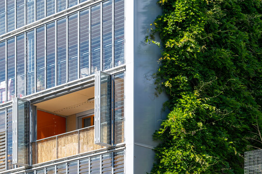 Green wall and apartment facade meet in La Confluence, Lyon, France, where windows, plants and wood recesses shape a residential courtyard view