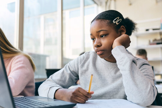 Teenage girl studying on laptop in classroom at junior high school
