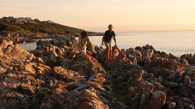 2 pre teen boys climbing and exploring the rocky coastline of DeKelders, South Africa