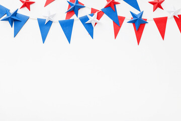 Obraz premium Patriotic red, white and blue paper bunting with origami stars on white background. Festive border with copy space for Independence, Memorial, Veterans or Flag day, Day, election campaign political
