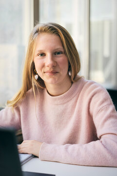 Portrait of smiling blond teenage girl sitting at desk in classroom at junior high school