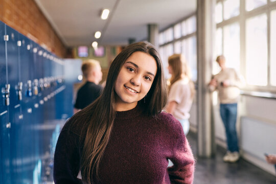 Portrait of smiling long haired teenage girl at school lobby