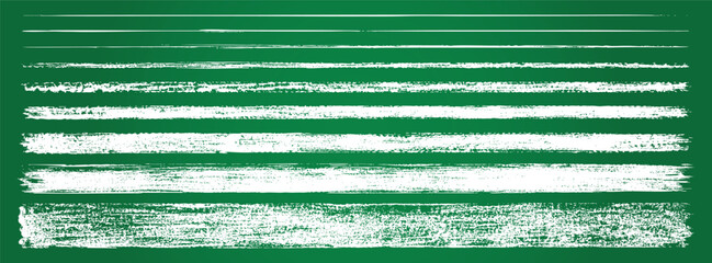 Collection of various hand-drawn white chalk lines, textures, and strokes isolated on a green blackboard background. © Zbrake Studio