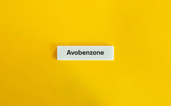 Avobenzone Sunscreen Ingredient Text on a White Block Against a Bright Yellow Background