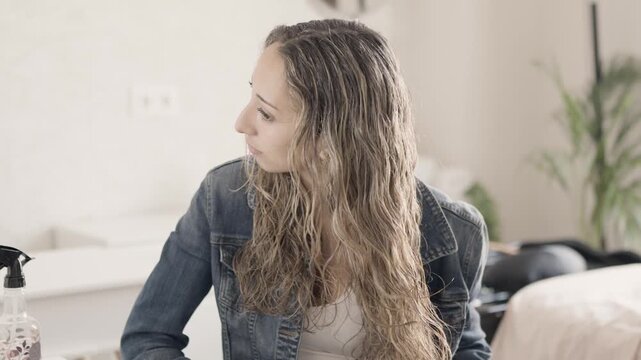 Young woman blow drying long curly hair