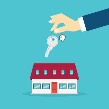 Hand holding key over the house. House buying