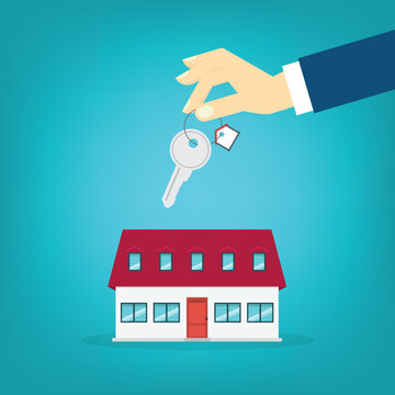 Hand holding key over the house. House buying