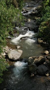 Vertical cinematic slow shutter footage of fresh clean river water cascading among stones, designed for endless seamless loop content.