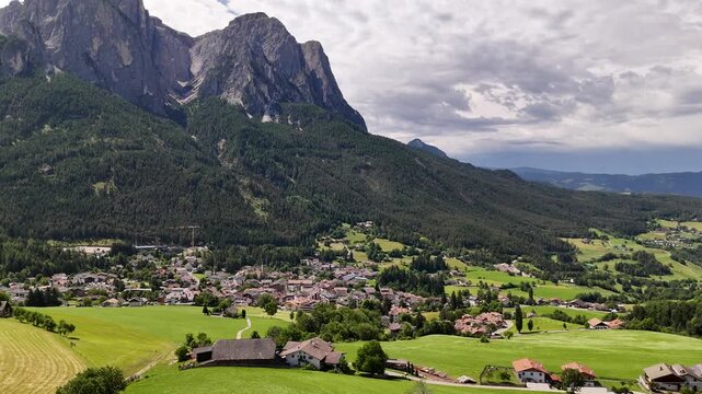 Stunning 4K drone footage panning around Castelrotto, a charming historic town in South Tyrol featuring the iconic St. Valentin Church, surrounded by the dramatic peaks of the Dolomites.