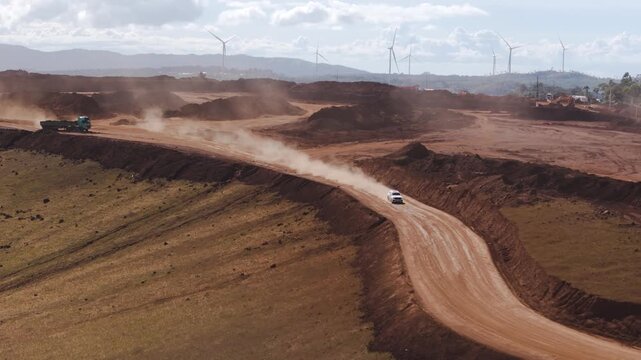 Cinematic front-facing shot of a White SUV driving at high speed along a dusty dirt road in a rugged landscape environment.
