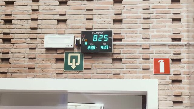 Monitor shows air quality and temperature changes in a public area with many people present - clean air CO2. RH