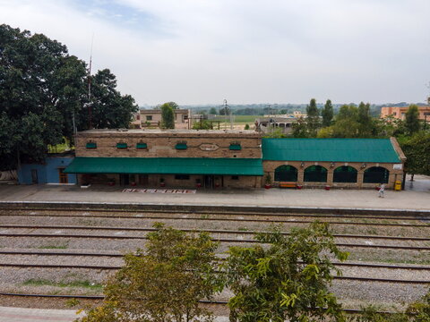 Aerial view of the historic Golra Sharif Railway Station featuring stone architecture, green roofs, and multiple train tracks in Islamabad, Islamabad Capital Ter, Pakistan.