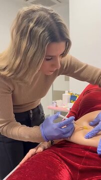 Female practitioner performing a subcutaneous injection treatment on a patient's abdomen