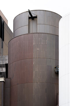 A cylindrical facade wraps a tower with metal cladding, where vertical curve and building architecture give the urban exterior quiet scale