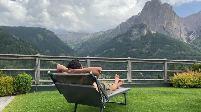 Stunning lifestyle footage of a man relaxing on a sun lounger soaking up the dramatic panoramic mountain views of the Dolomites, South Tyrol &mdash; the ultimate alpine relaxation moment.