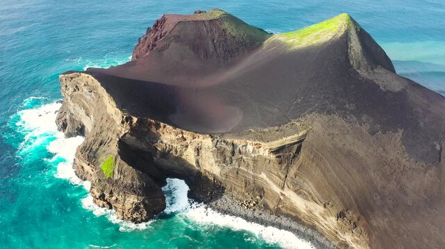 An aerial view of Capelinhos Volcano with volcanic slopes meeting the Atlantic Ocean on Faial Island, Portugal