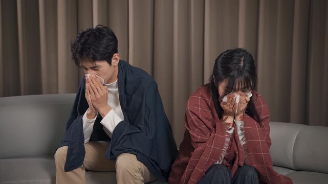 Tired couple family man woman blowing nose into paper tissue in bedroom at night, experiencing illness virus spread for infection, sinus and cold symptoms, indicating fatigue potential viral infection