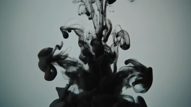 Abstract black ink cloud diffusing in liquid against light background with minimalist artistic dark smoke patterns swirling in water