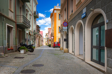 Obraz premium Narrow cobblestone street with colorful buildings in Olbia, Sardinia, Italy - background or travel wallpaper
