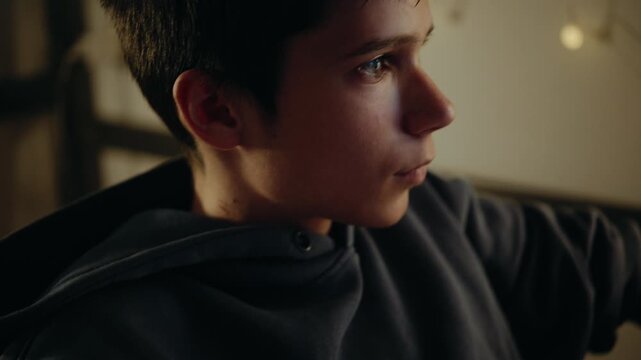 A teenage boy plays a video game on a computer at night. The shot focuses on his hand on the gaming mouse and then his concentrated face.