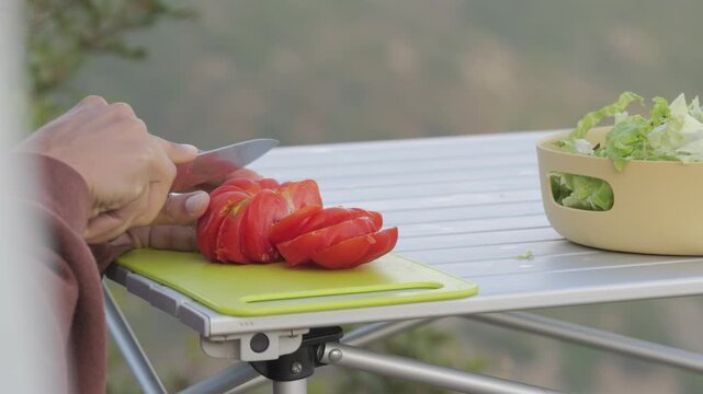 Cutting tomato in van life outdoor kitchen, Italy