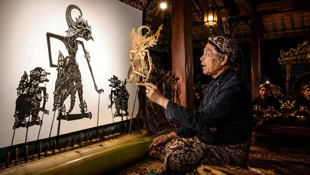Man creating traditional balinese shadow puppets for a cultural performance in indonesia with intricate designs