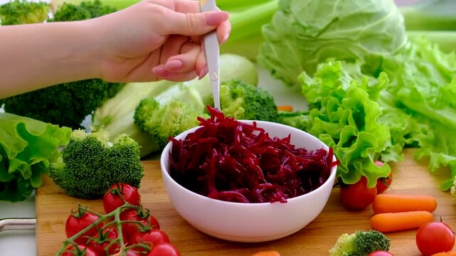 Fork picking grated boiled beetroot from white plate Boiled burgundy beet on a white plate. Boiled vegetables before cooking. Ripe boiled beet close-up on the kitchen table