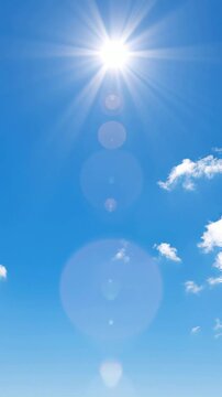 Bright sun shining in clear blue sky with soft clouds