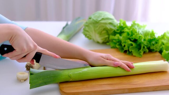 cut the leek Female hand slicing fresh leek onion for vegetable lunch
