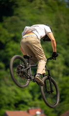 Fototapeta premium Young cyclist flying through the air on mountain bike during freestyle jump, showcasing athletic skill, adventure lifestyle and extreme outdoor sports