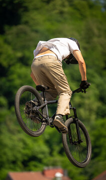Young cyclist flying through the air on mountain bike during freestyle jump, showcasing athletic skill, adventure lifestyle and extreme outdoor sports