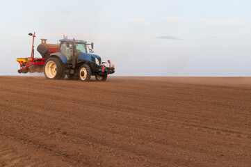 Fototapeta premium Tractor plowing and sowing on agricultural field in spring