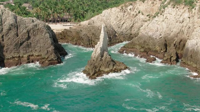 Drone pull back shot at Dedo de Dios iconic landmark, located at Maruata Beach between rugged rocky volcanic cliffs