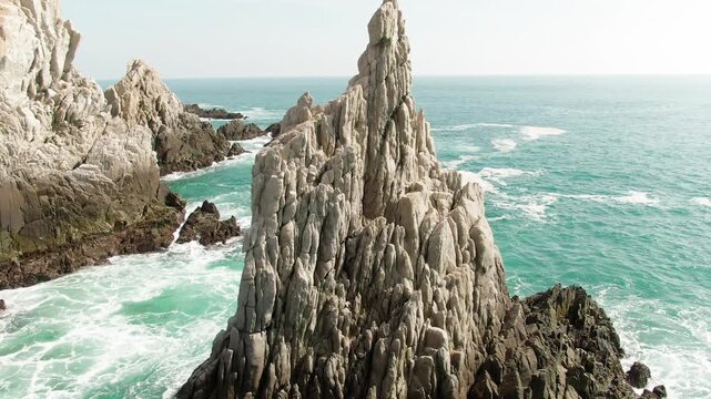 Close up drone view of iconic Dedo de Dios sea stack with detailed rock textures above turquoise Pacific waters.