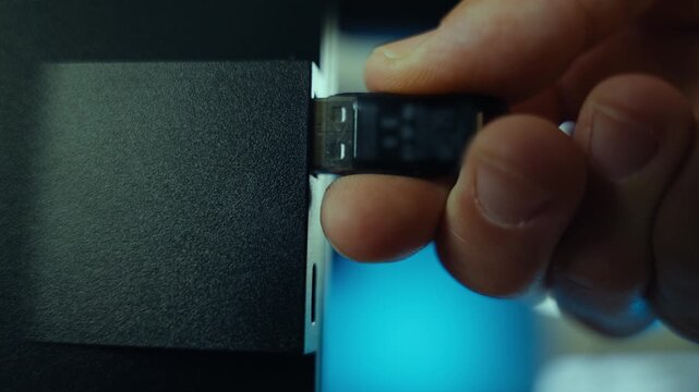 Flash drive inserted into computer in office or house by person hacker or spy. Installing software or malware into system pc. Close up on hand plugging memory stick. Suspicious cyber data activity