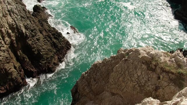Aerial reveal shot of Dedo de Dios sea stack framed by cliffs and turquoise Pacific waters in Michoacan, Mexico