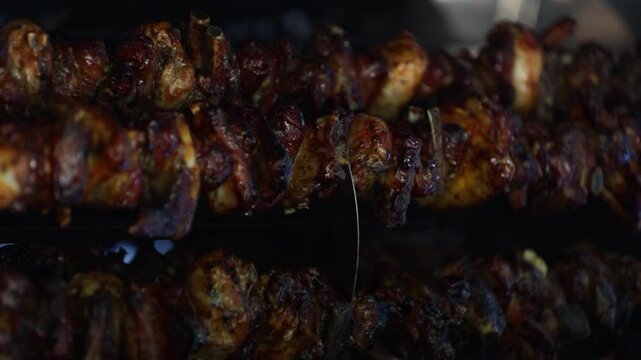 Traditional Spiedo Bresciano slowly cooking on rotating skewers, showcasing authentic Italian cuisine, culinary heritage and regional gastronomy from Brescia, Lombardy.
