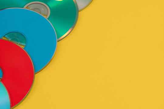 Several compact discs different colors for laser players they lie on a yellow background.s.